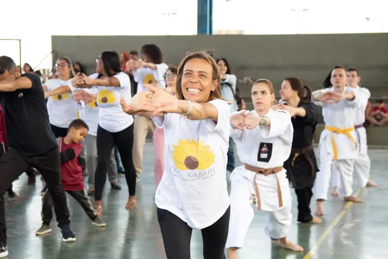 Voluntária sorri durante uma atividade física em grupo numa quadra.